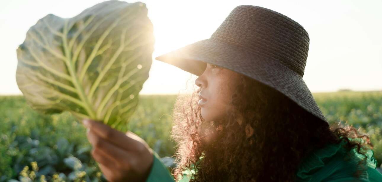A woman holding up a single collard green leaf. Image: Ron Lach