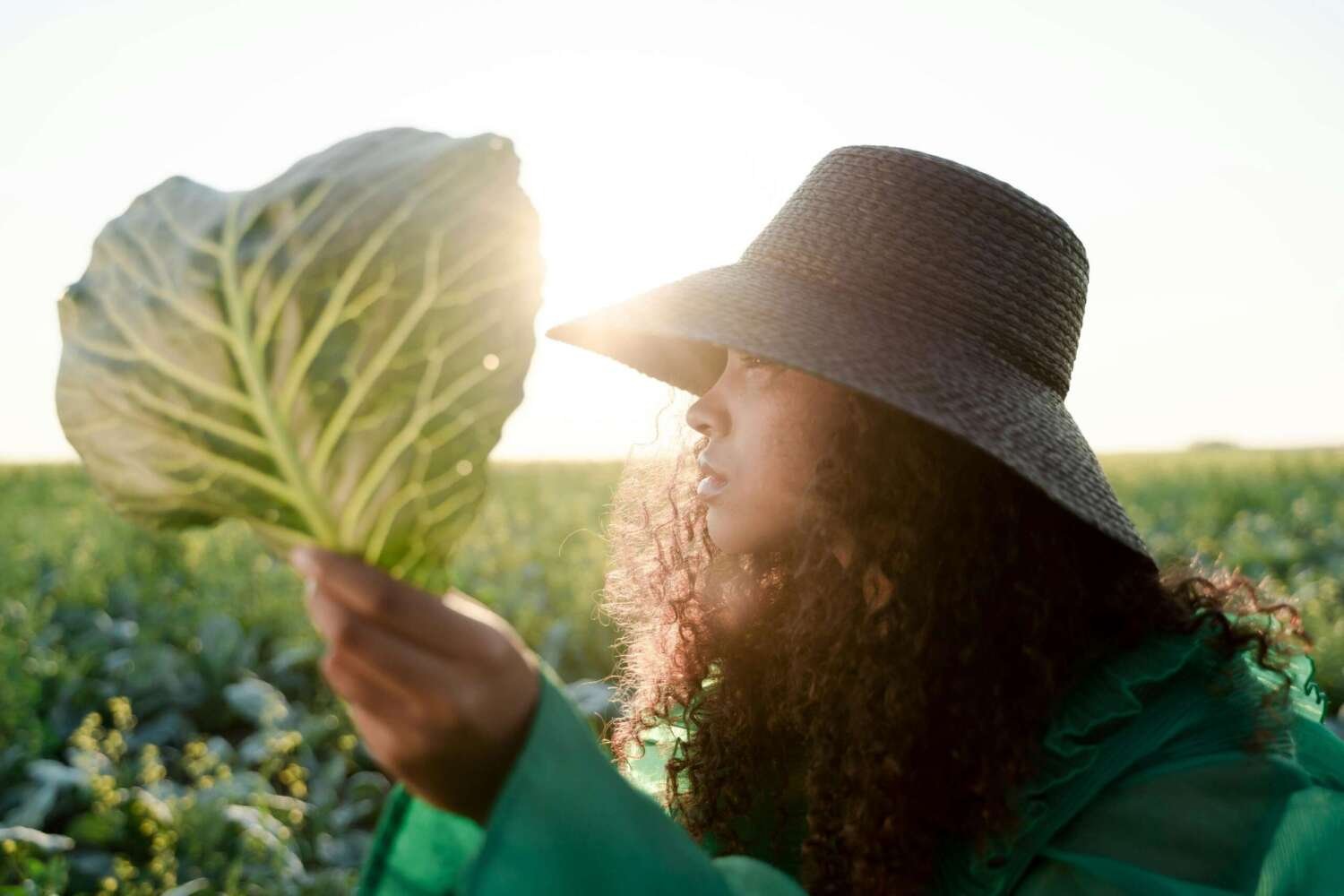 A woman holding up a single collard green leaf. Image: Ron Lach